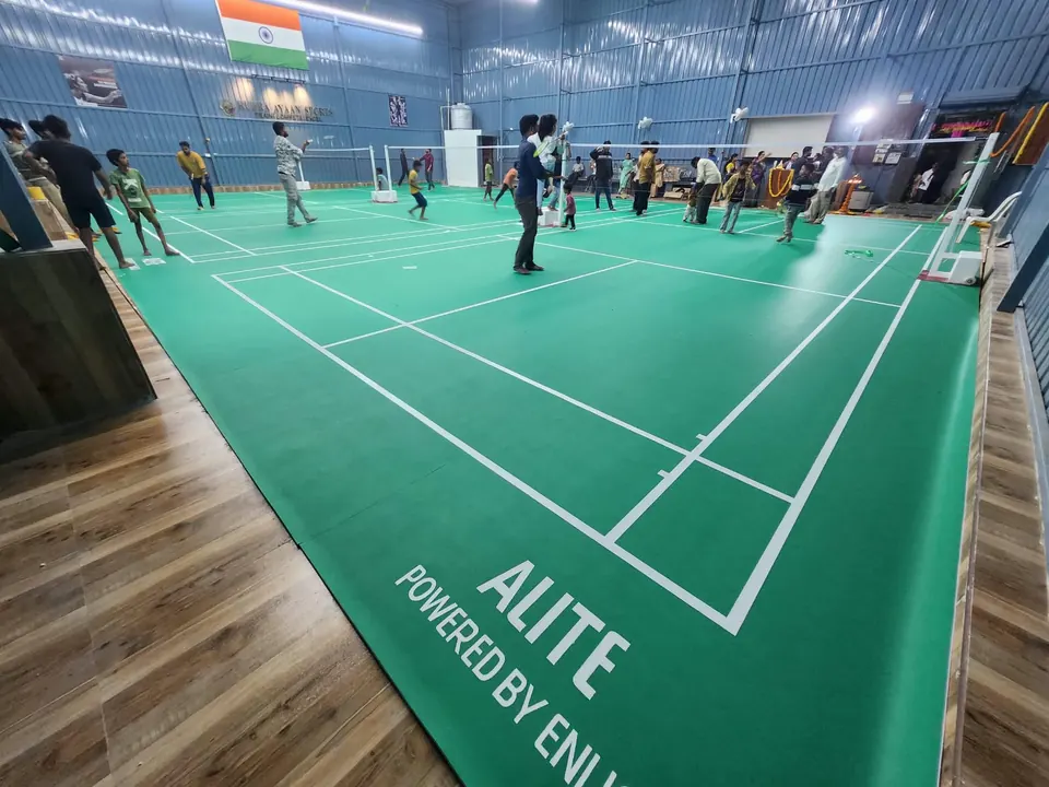 Families and children on the courts at Rudra Ayaan Sports, a multi-court indoor badminton hall built by Kelysports, with wood-finish surrounds.