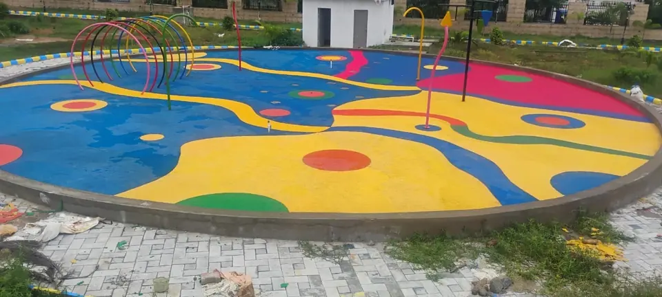 Circular EPDM play zone with blue, yellow and pink patterns and play hoops.