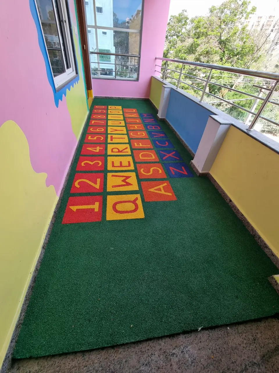 Green EPDM balcony floor with a keyboard-style alphabet and number grid.