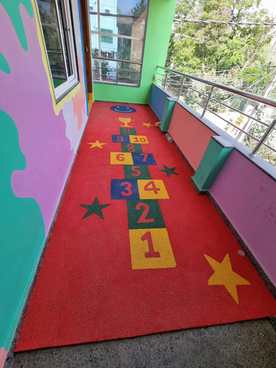 Red EPDM hopscotch track with yellow stars, installed by Kelysports on a balcony floor.