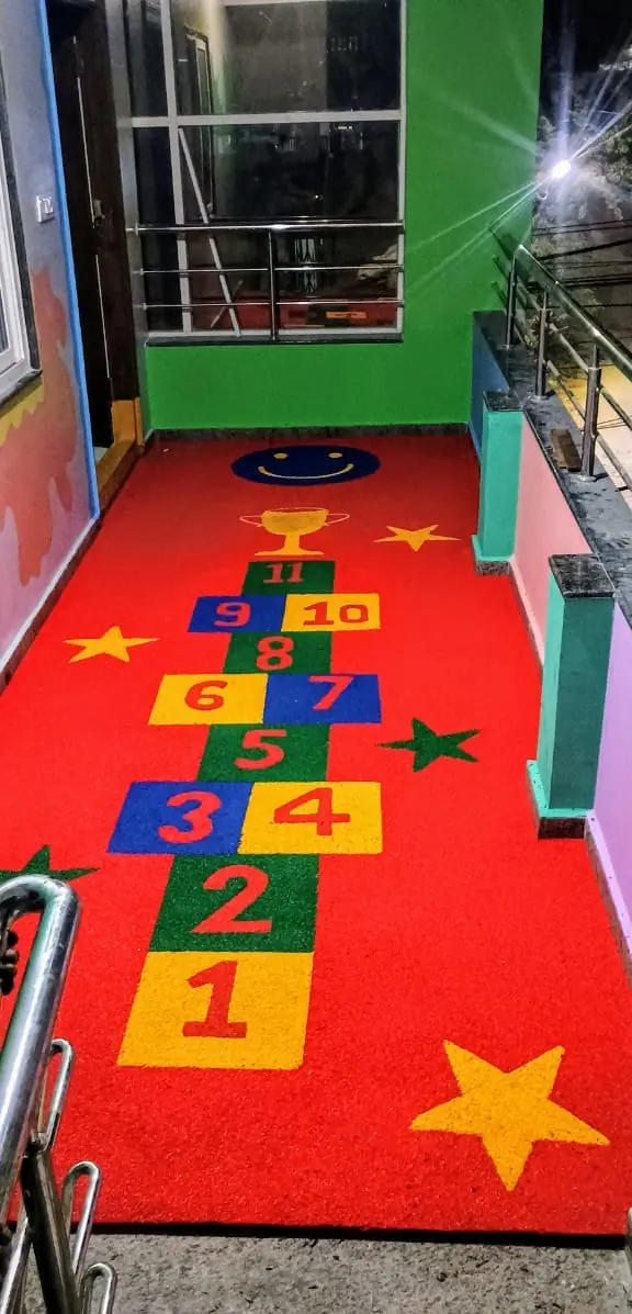Red EPDM hopscotch flooring with numbered squares and star inlays in a narrow play corridor.