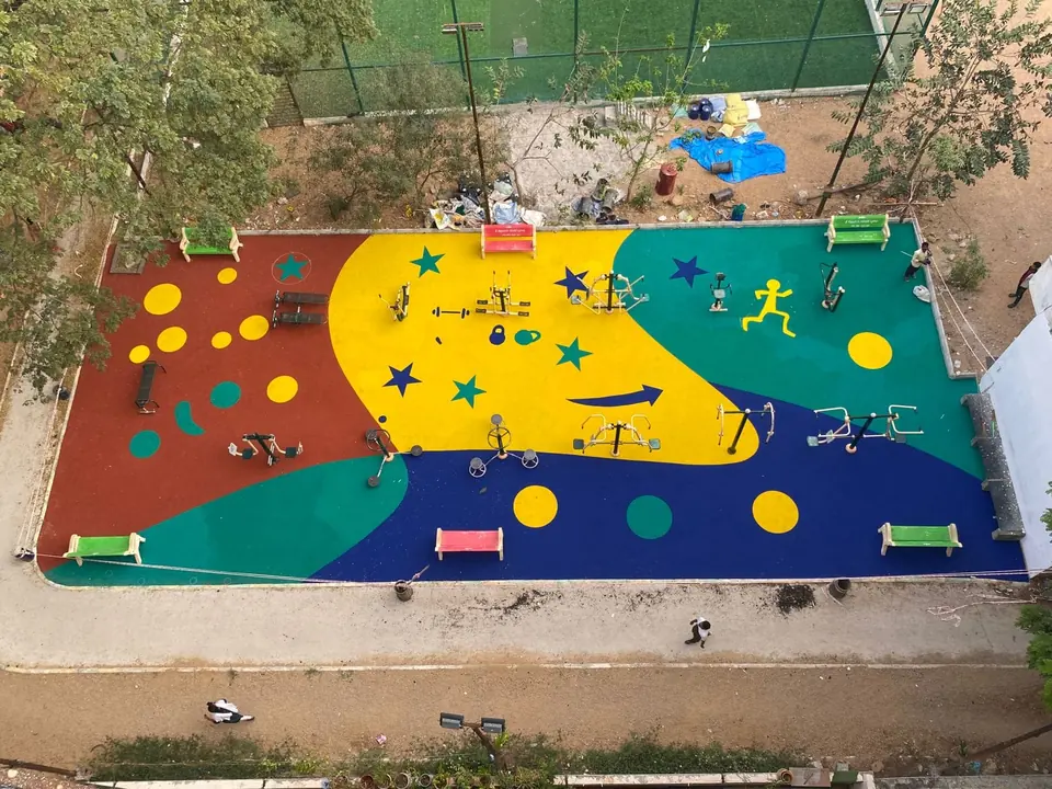 Aerial view of an outdoor gym with multicolour EPDM flooring by Kelysports, with star and runner graphics and fitness equipment.