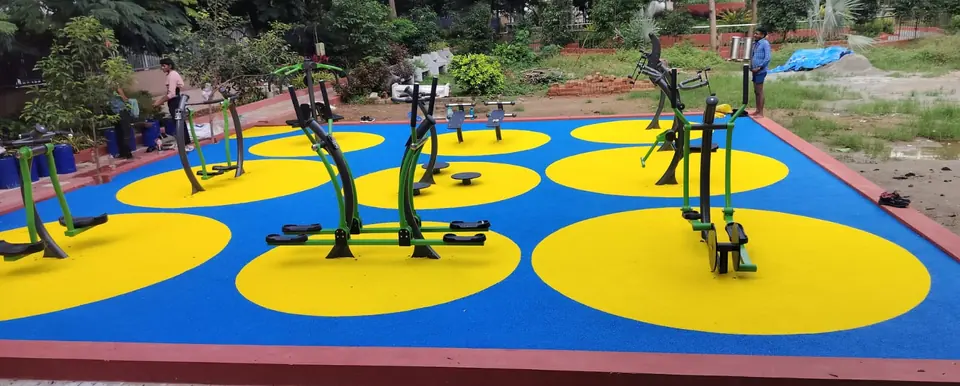 Outdoor gym equipment on blue EPDM rubber flooring with large yellow circles.