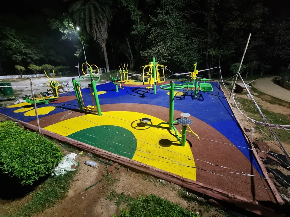 Outdoor gym on blue, yellow, green and brown EPDM flooring, photographed at night.