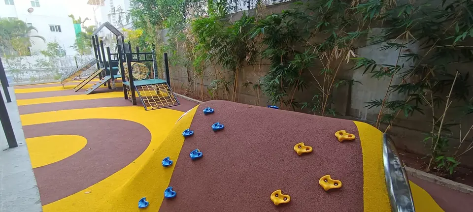 EPDM-surfaced play mound with climbing holds, finished in brown and yellow.