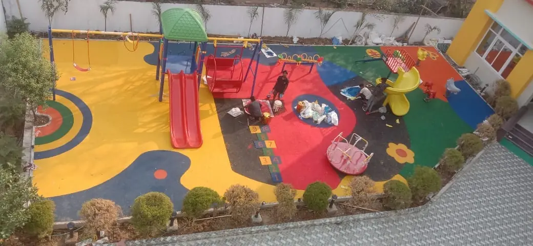 Aerial view of a playground during EPDM flooring installation, with colour zones and play equipment.