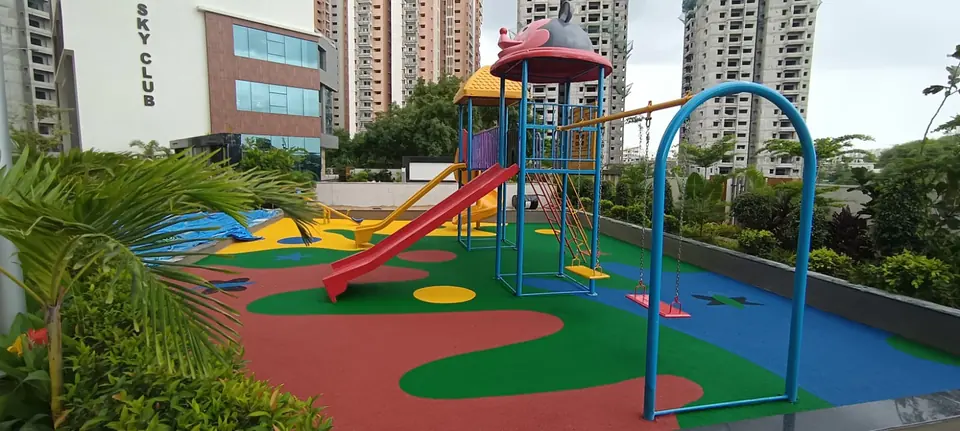 Red, green and blue EPDM rubber flooring with wave patterns around a playset and swing at a residential playground.