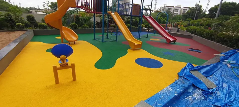 Yellow, green and red EPDM rubber flooring under a children's playset with slides at a residential playground.