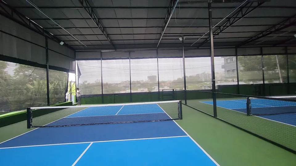 Close view of a Rayadurgam pickleball court: light and dark blue playing areas, crisp white lines and the net across the court.