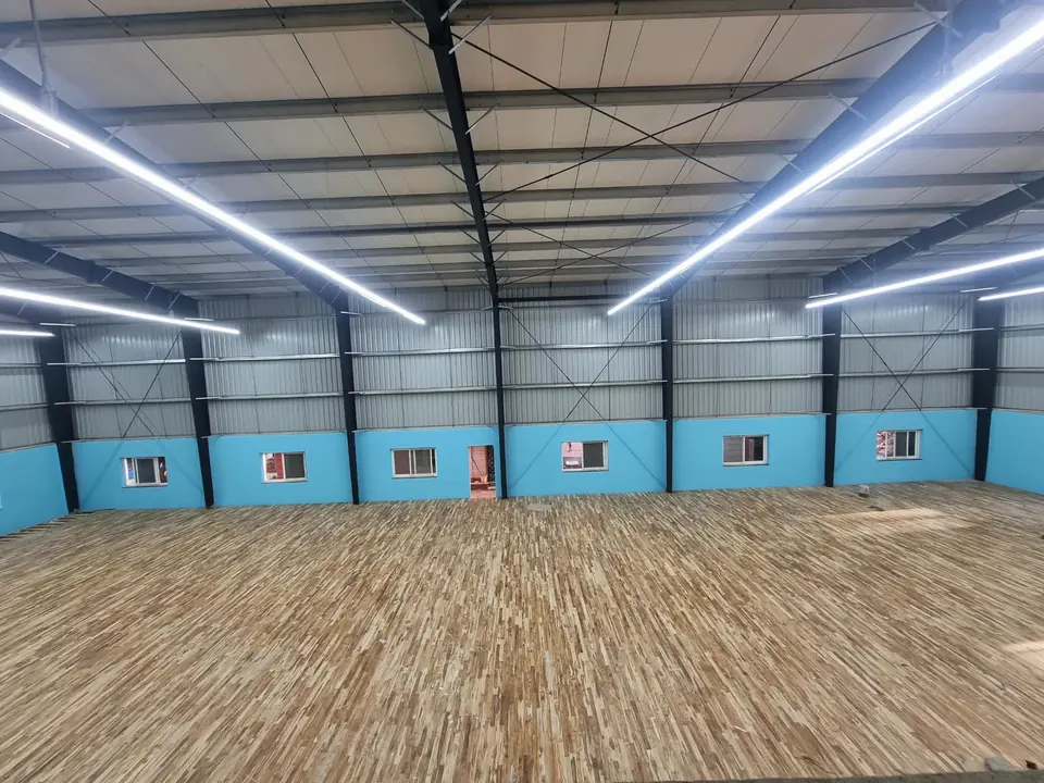 Teak Wooden Badminton Court Flooring by Kelysports across a large steel-framed sports shed with linear LED lighting.
