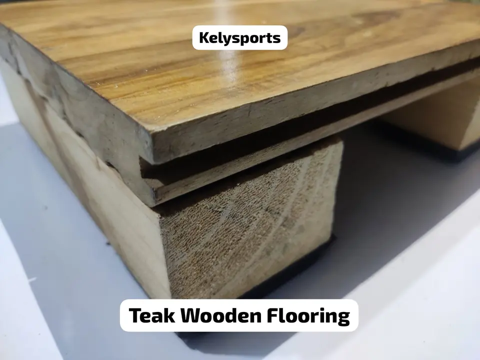Cut-away sample of Kelysports teak wooden flooring showing the teak top board, a board layer beneath and a timber batten on a dark pad.